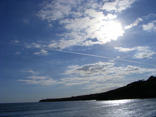 Čiara za lietadlom predeľujúca oblohu nad oceánom